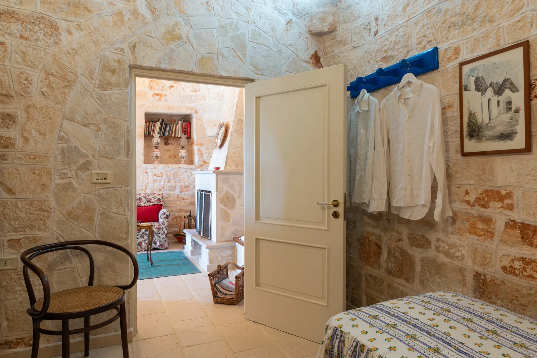 Una habitación con paredes de piedra, una puerta abierta y una cama.