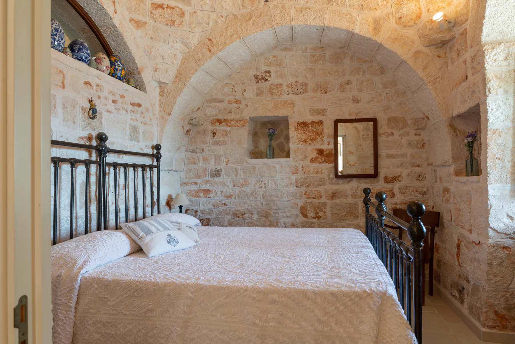 Un dormitorio con una cama bajo un arco de piedra.