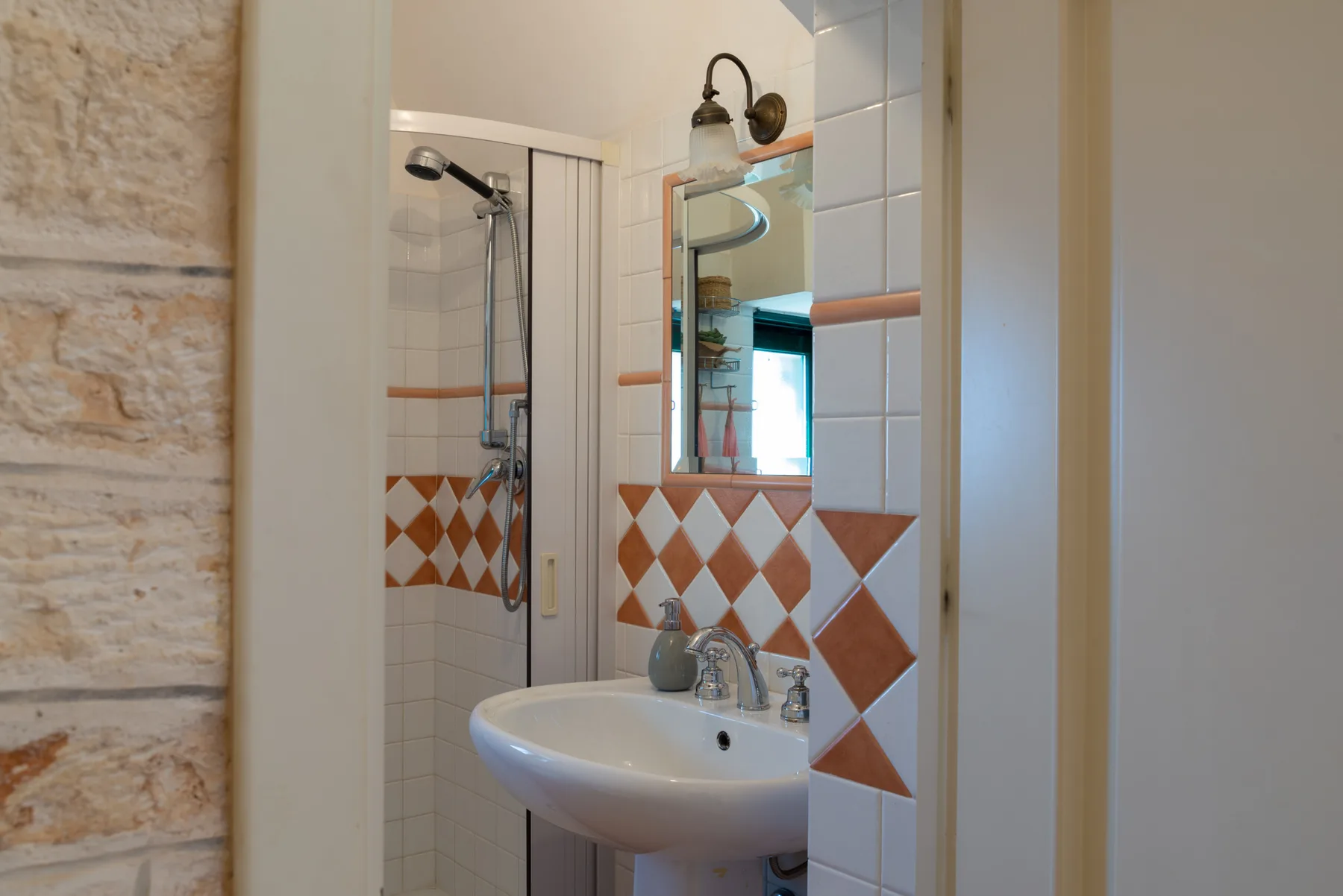 Un baño con azulejos, lavabo de pared y ducha.