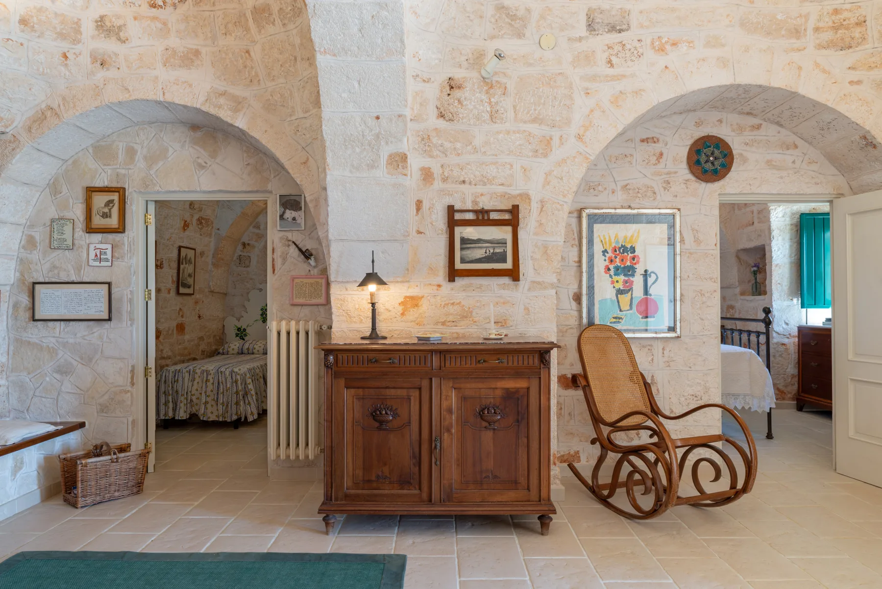 Una habitación con paredes de piedra, arcos y un mueble de madera.