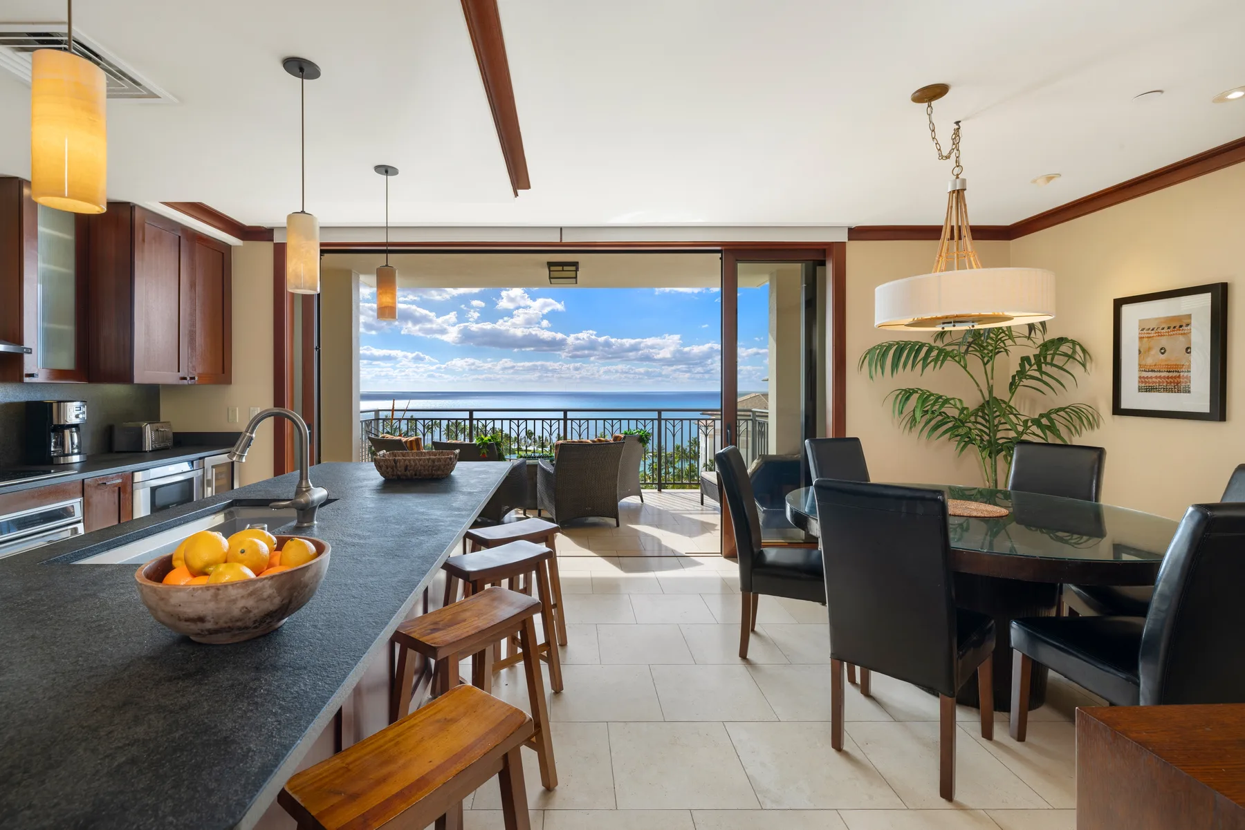 Una cocina abierta y comedor dan a un balcón con vista al mar.