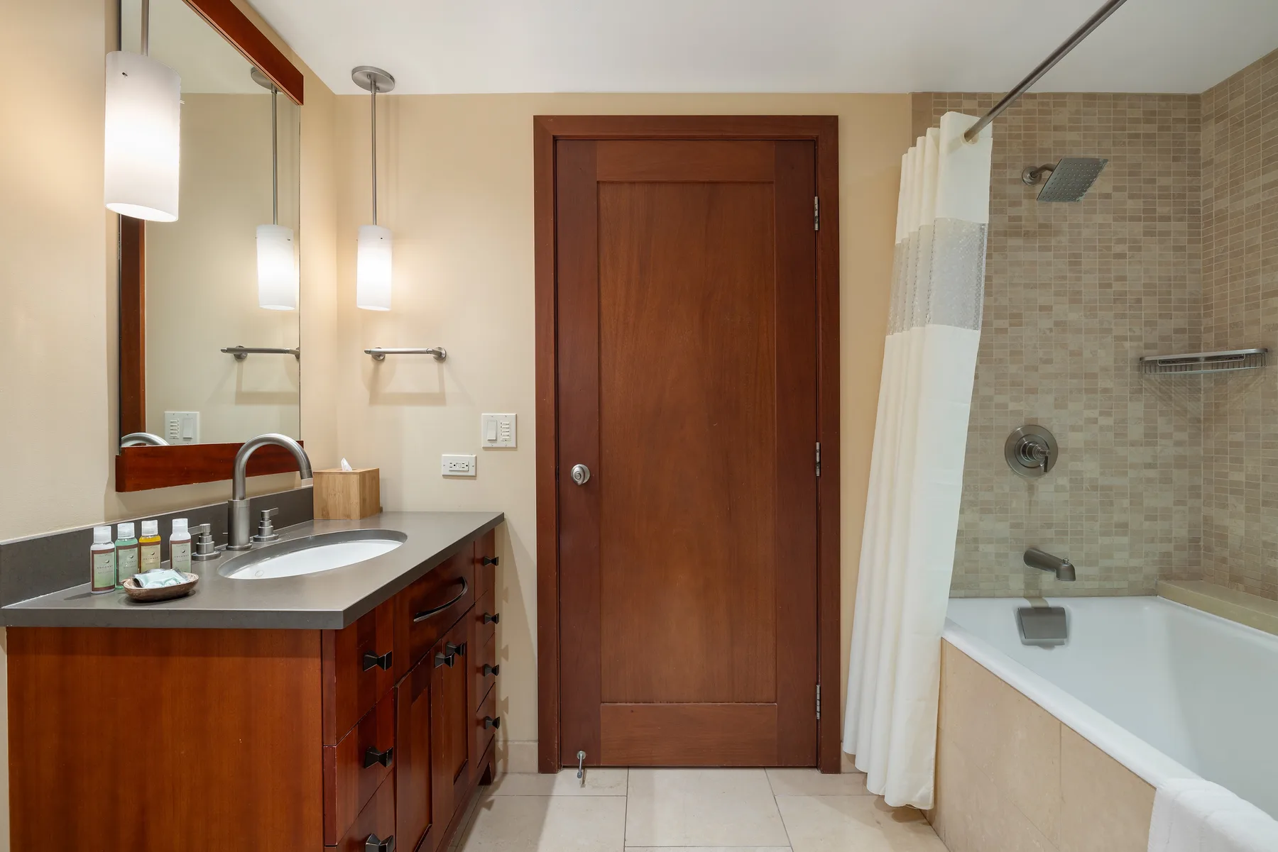 Un baño con tocador, espejo y bañera detrás de una cortina de ducha.