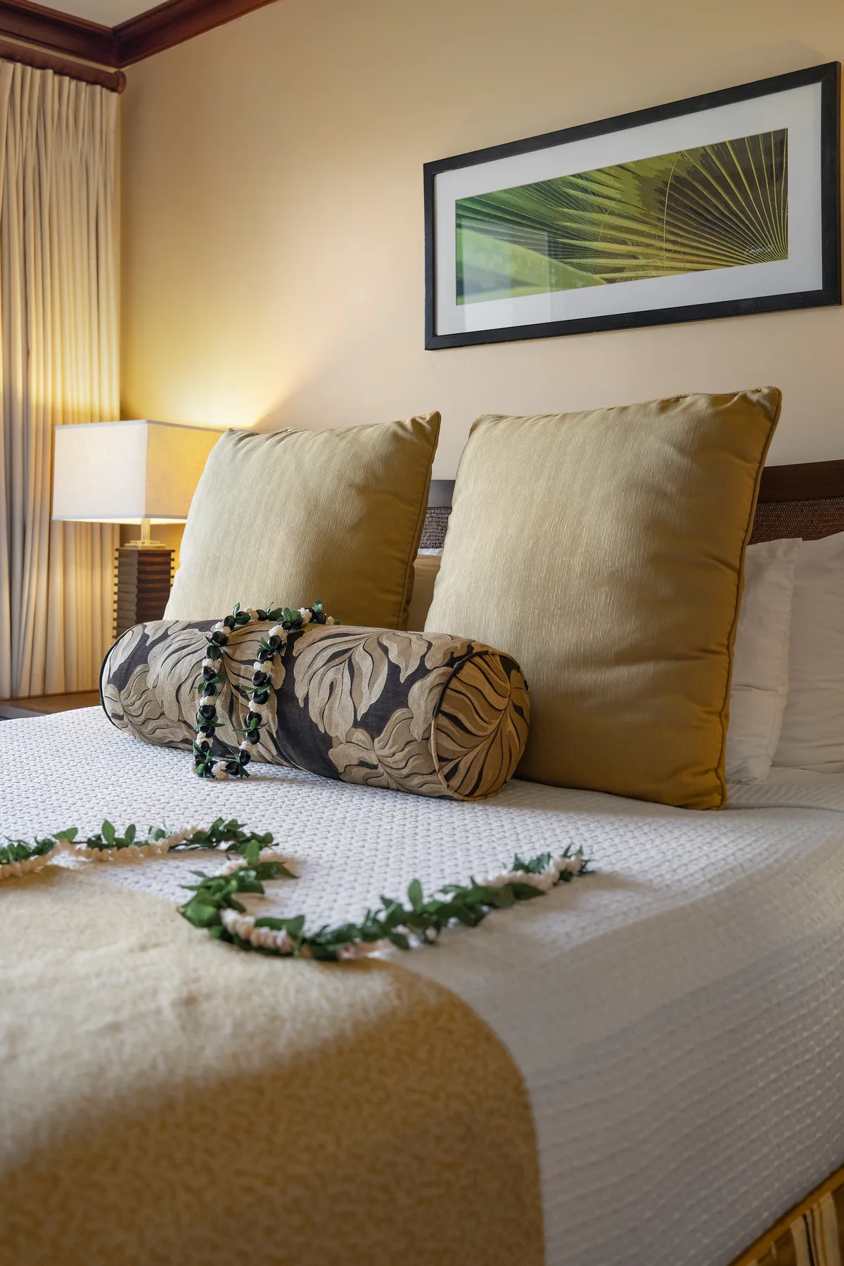 Un dormitorio con una cama bien arreglada, cojines decorativos y una obra enmarcada.