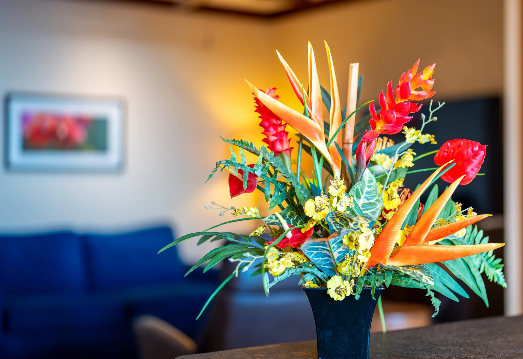 Un colorido arreglo de flores tropicales está sobre una mesa en una sala de estar.