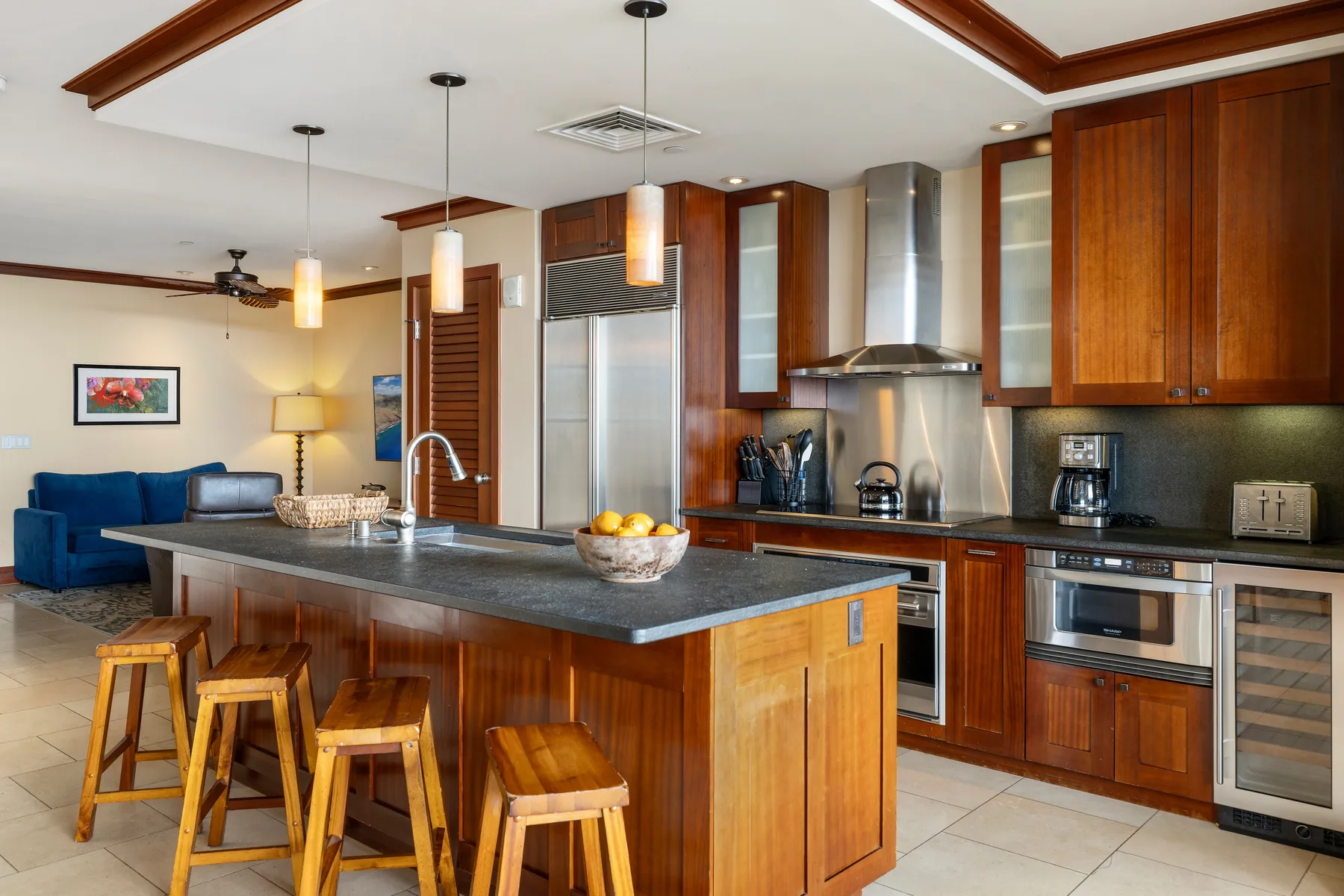 Una cocina con una isla grande y gabinetes de madera, abierta a una zona de estar.