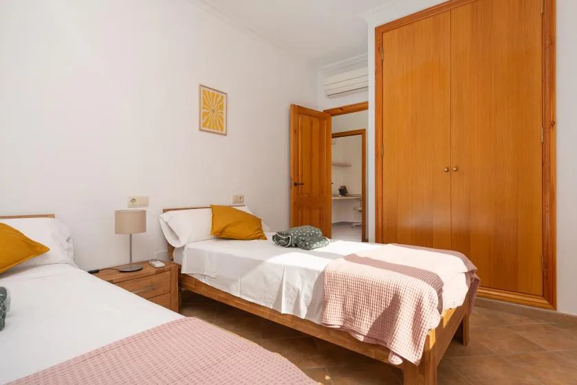 Un dormitorio con dos camas, armarios de madera y una mesita de noche.