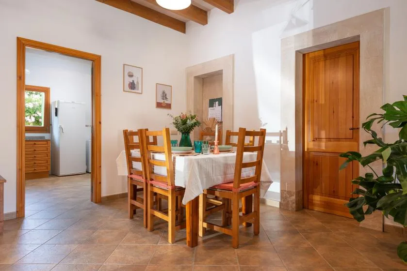 Un comedor con una mesa de madera, sillas y una planta en maceta.