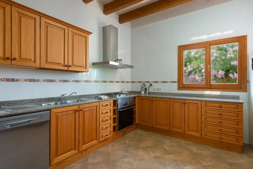 Una cocina con gabinetes de madera, una encimera y una ventana con vista a la vegetación.