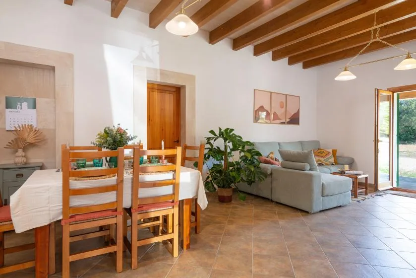 Sala de estar y comedor con una mesa de madera, asientos y vigas expuestas en el techo.