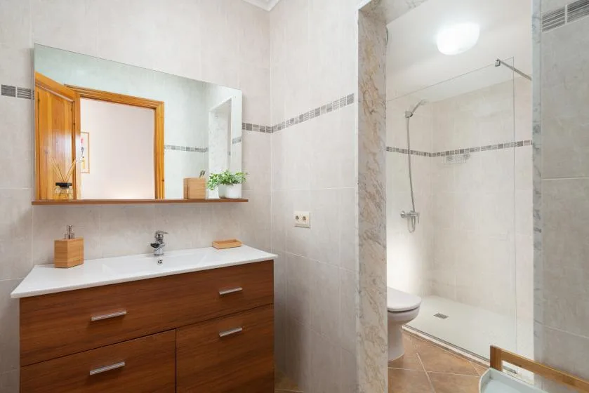 Un baño con lavabo, espejo y ducha de cristal.