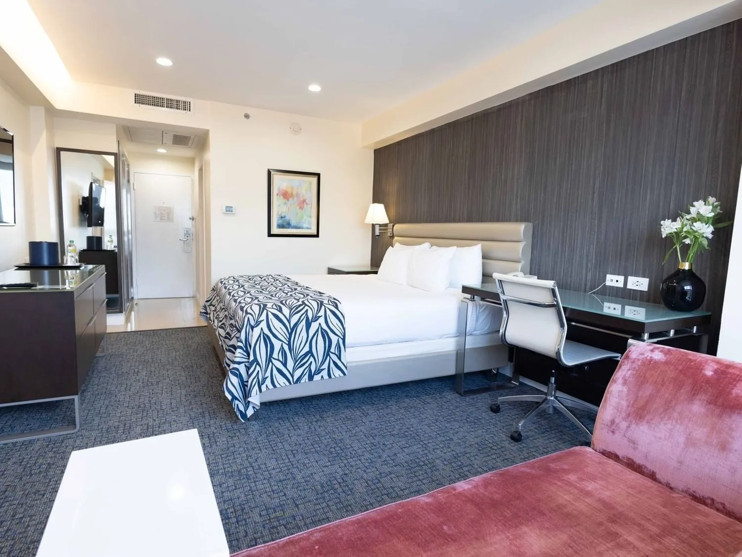 Cama, escritorio y zona de estar en una suite Deluxe de un dormitorio con cama king.