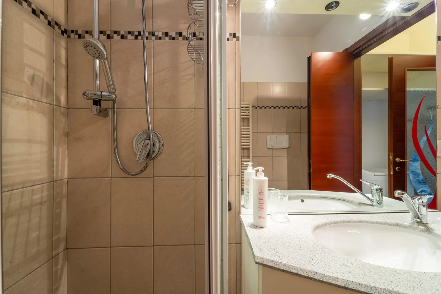 A bathroom with a glass-enclosed shower and a sink counter.
