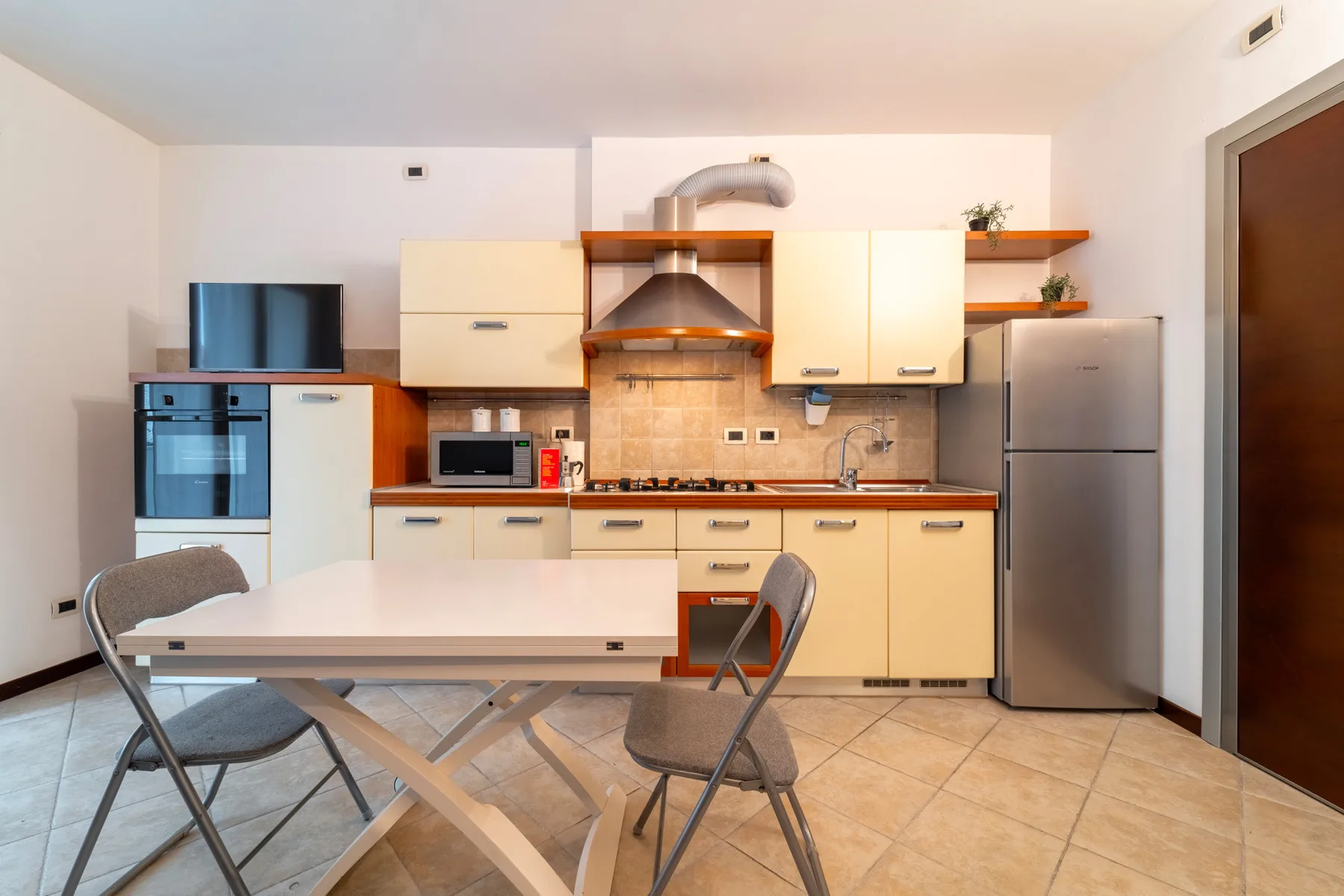 A kitchen with light-colored cabinets, appliances, and a dining table.