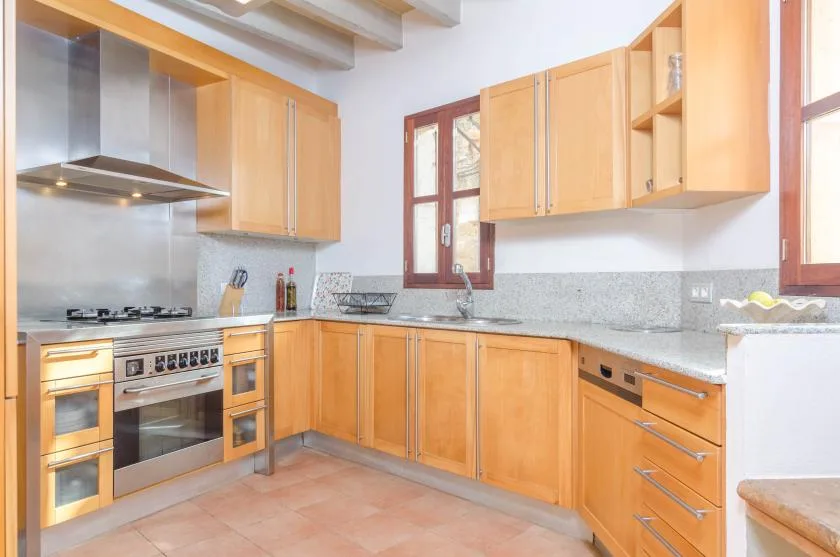 Una cocina luminosa con gabinetes de madera, encimera y electrodomésticos de cocina.