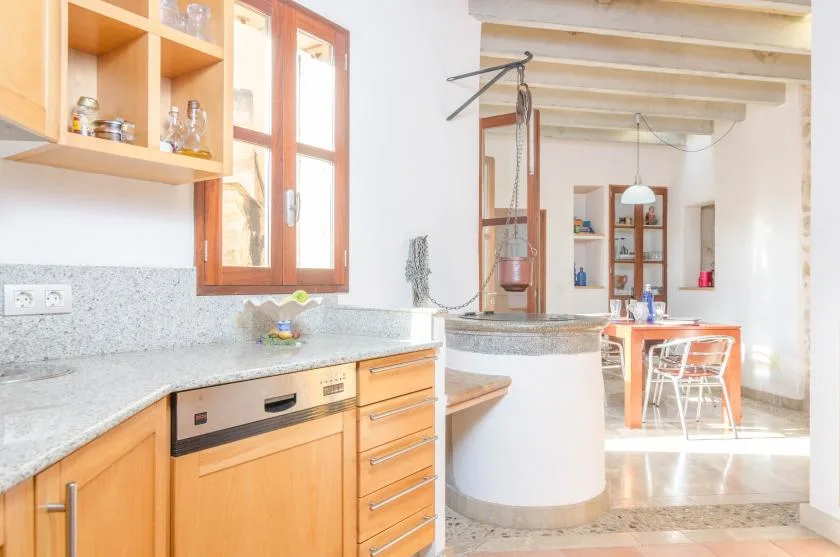 Una encimera de cocina con gabinetes de madera da a un comedor.