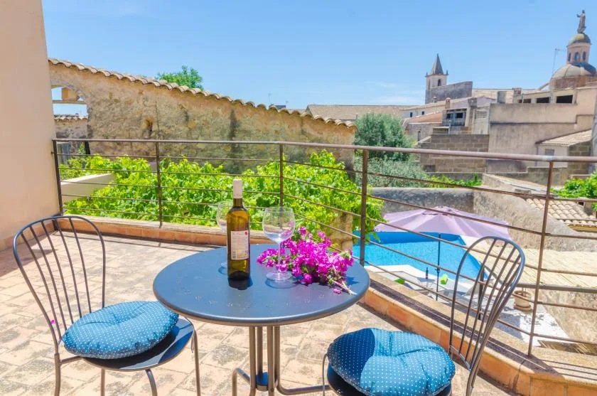 Una terraza con mesa redonda y asientos da a tejados y una piscina.
