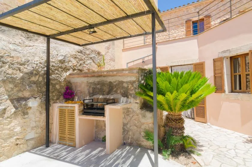 Un patio al aire libre con una encimera fija bajo un toldo de listones.