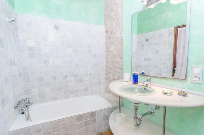 Un baño con bañera y lavabo bajo un espejo grande.