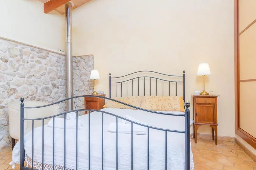 Un dormitorio con una cama de metal, mesitas de noche y una pared decorativa de piedra.