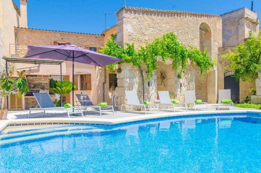 Una piscina al aire libre con asientos reclinables y una sombrilla grande.