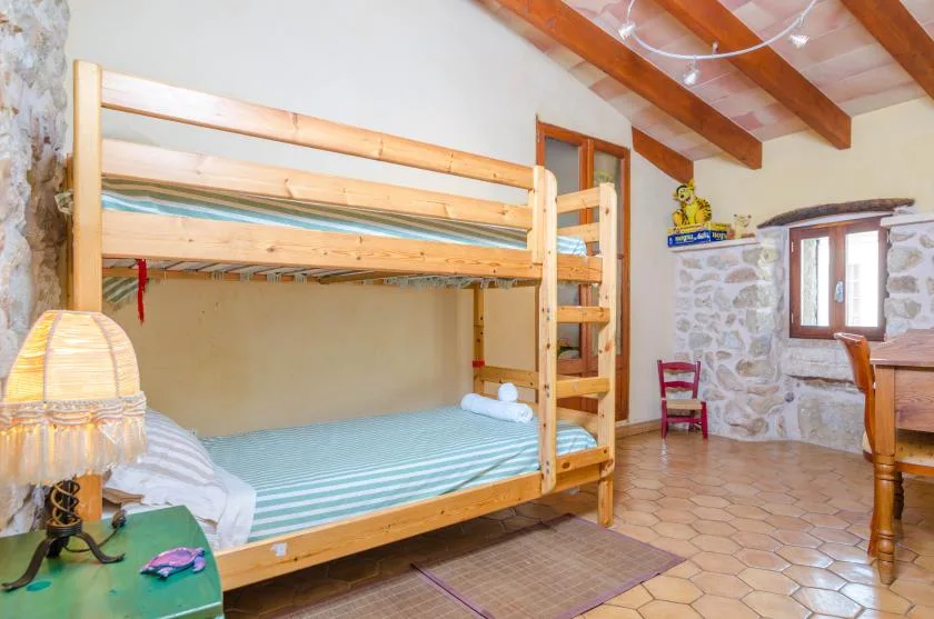 Un dormitorio rústico cuenta con una litera de madera junto a una pared de piedra.