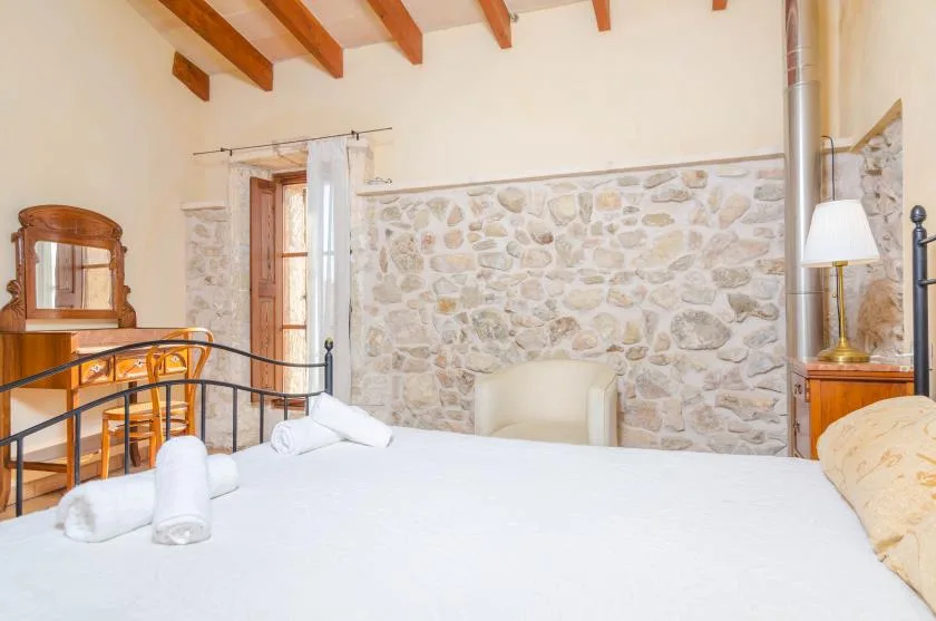 Un dormitorio con una cama, una pared de piedra y vigas de madera a la vista.