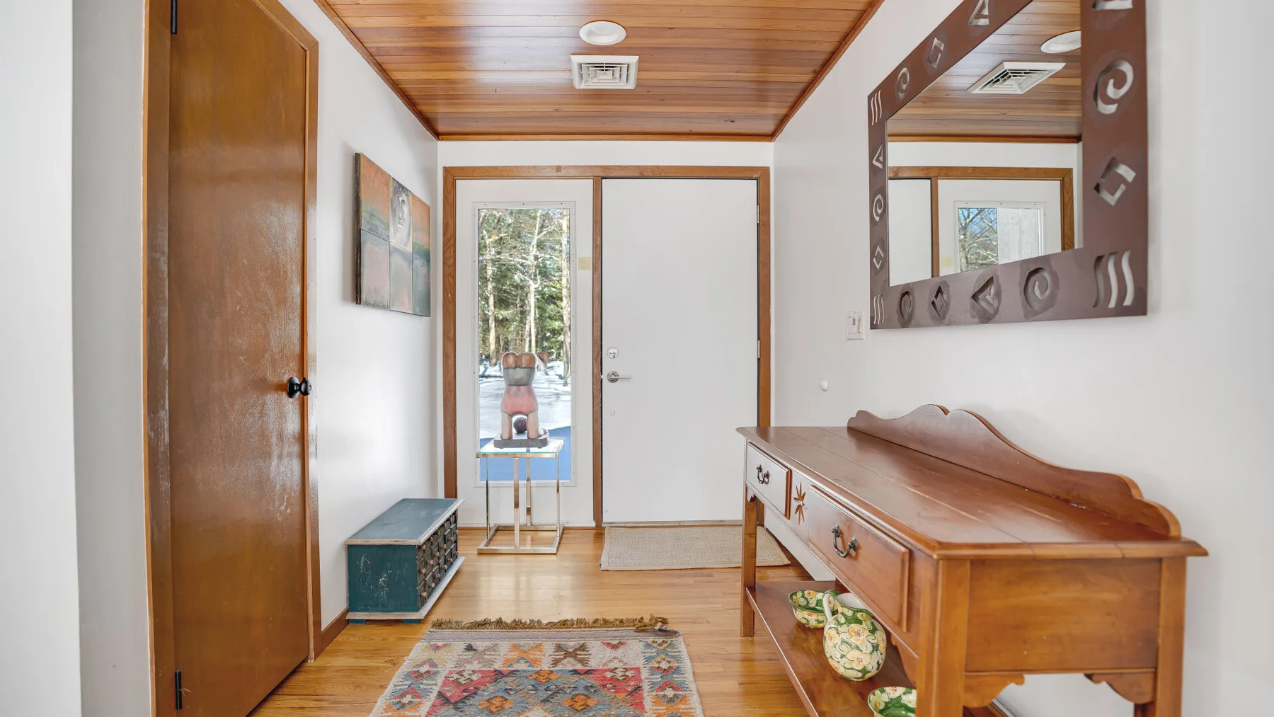 A wood-trimmed entryway with a console table and a glass door.