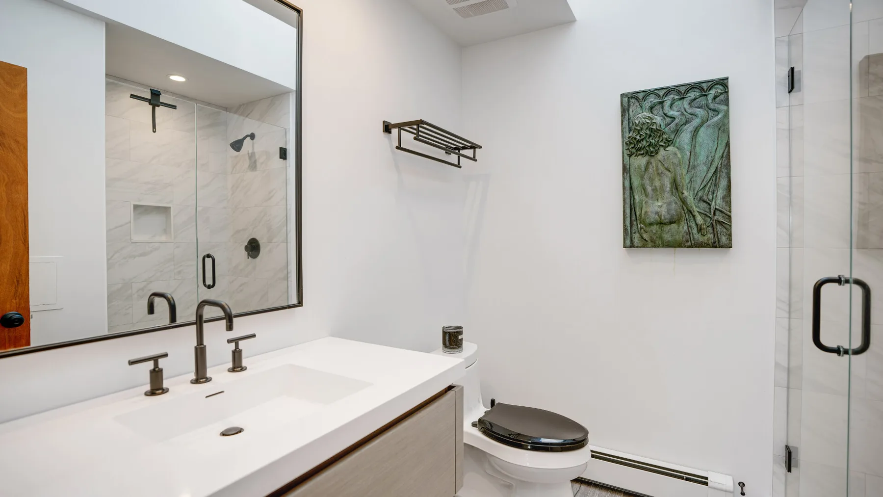 A bright bathroom with a wide vanity, toilet, and glass shower.