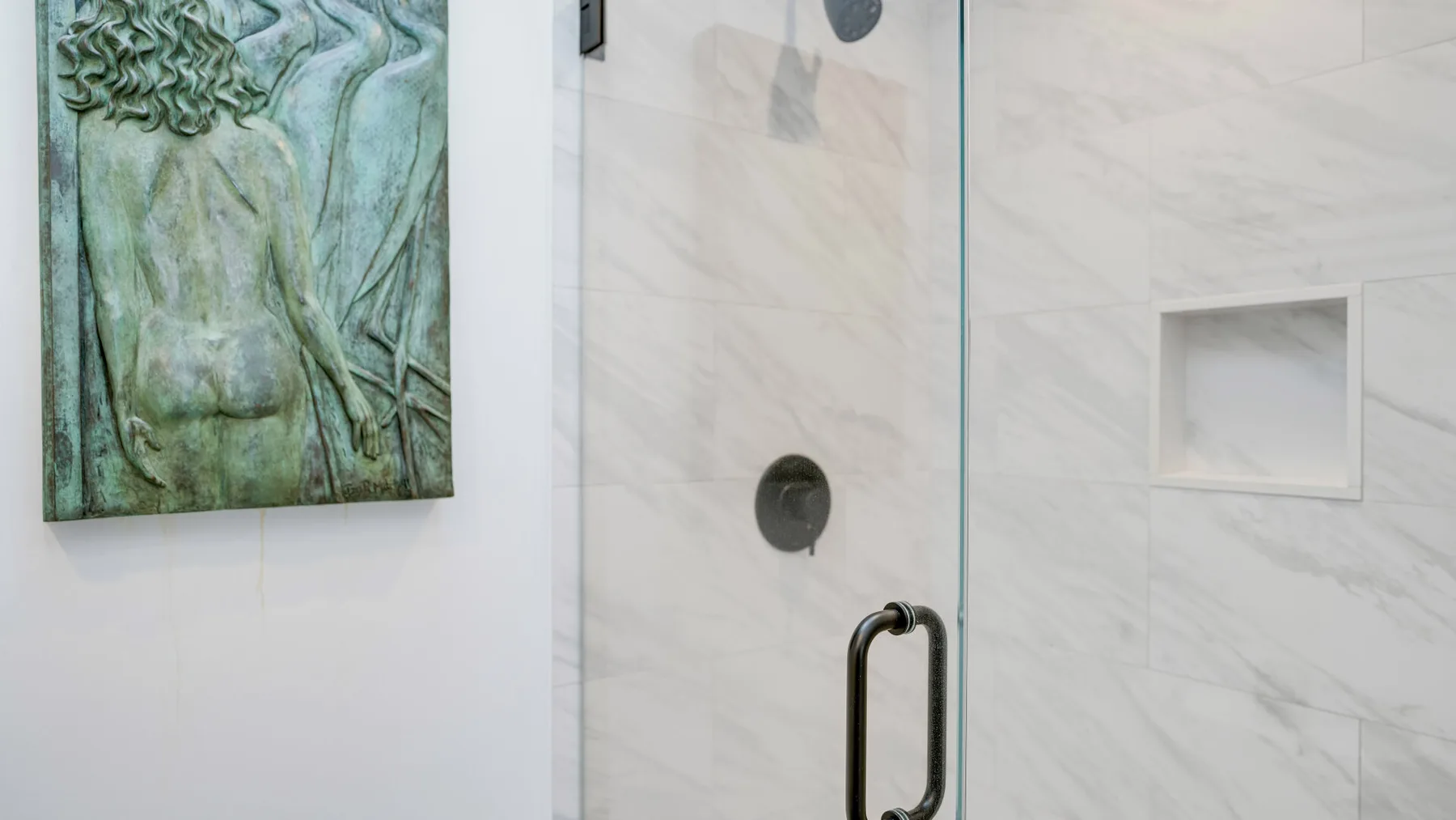 A bathroom shower area with light veined walls and a wall-mounted control.