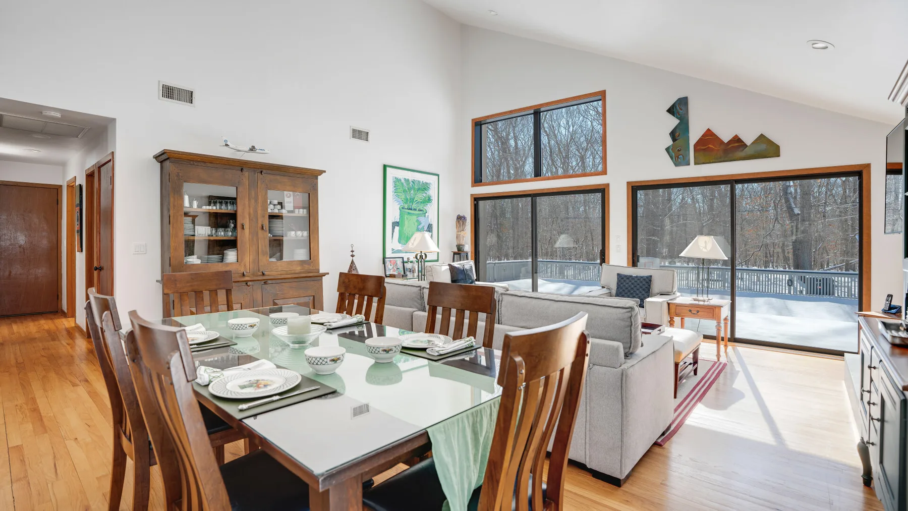 A bright dining and living area has a set table beside large windows.
