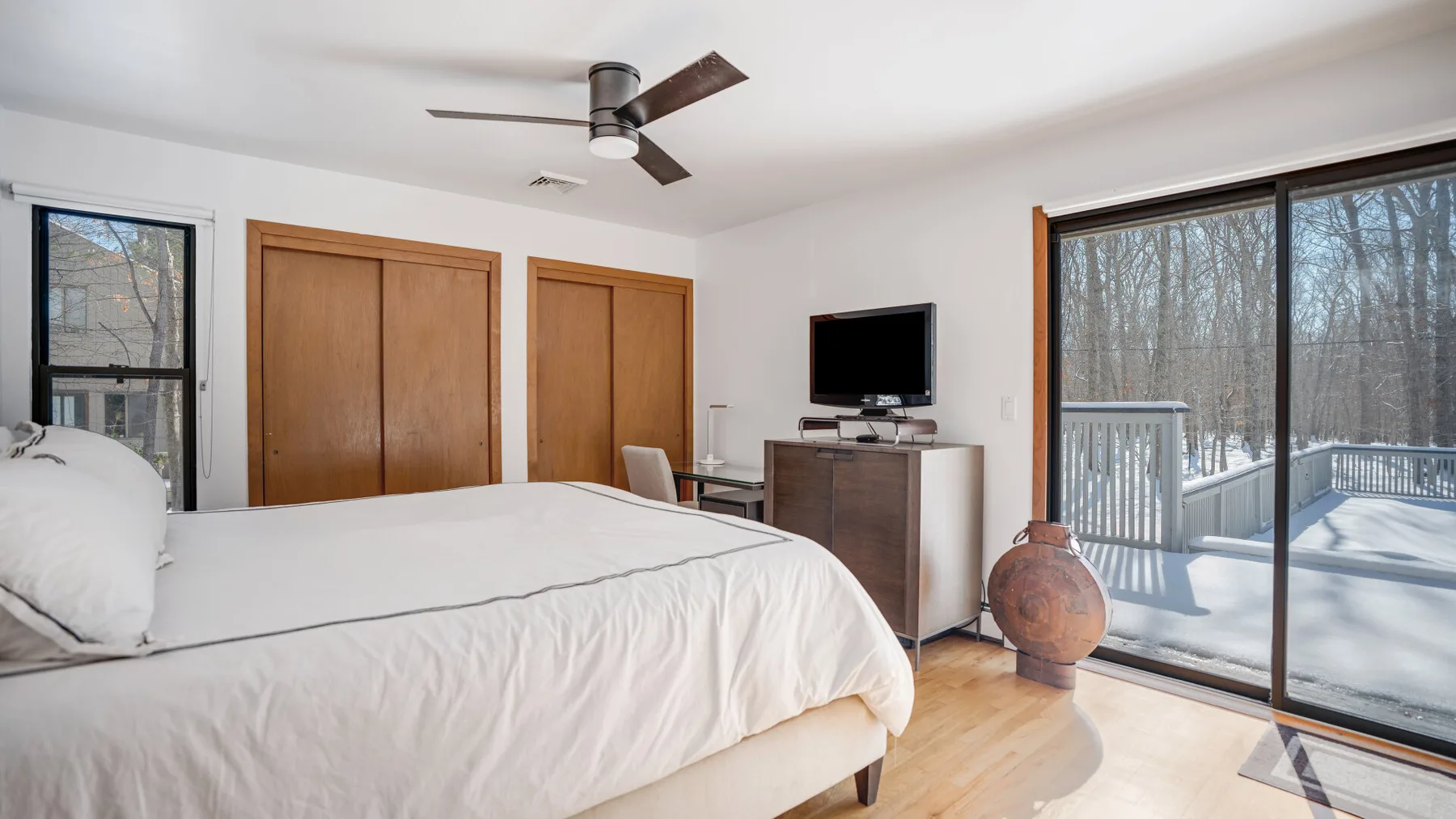 A bedroom with a large bed, wooden closet doors, and sliding glass doors.