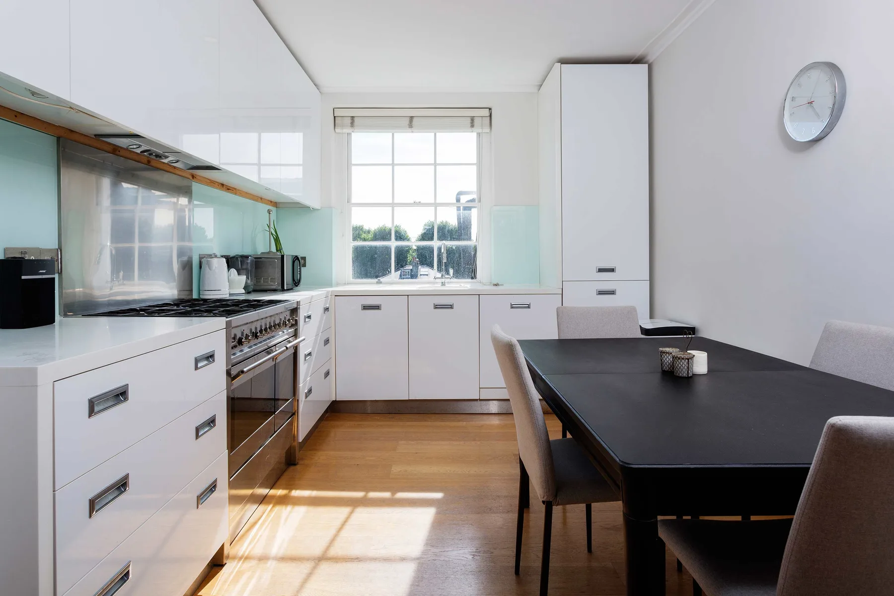 A bright kitchen and dining area with white cabinets and a dark table.