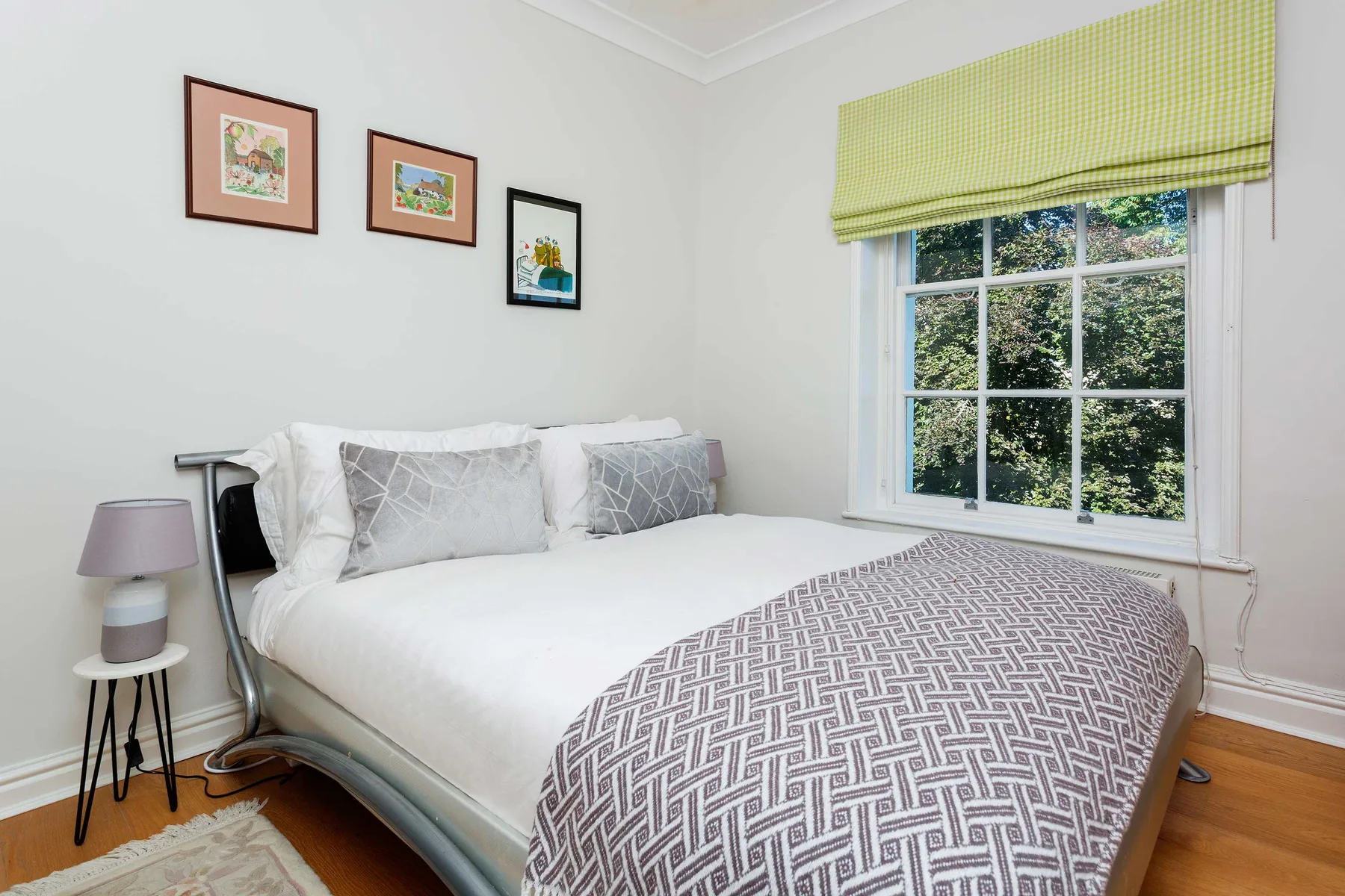A bright bedroom with a neatly made bed beside a large window.