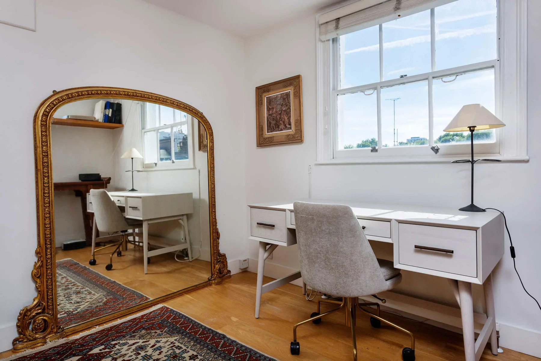 A bright home office with a desk and chair beside a large window.