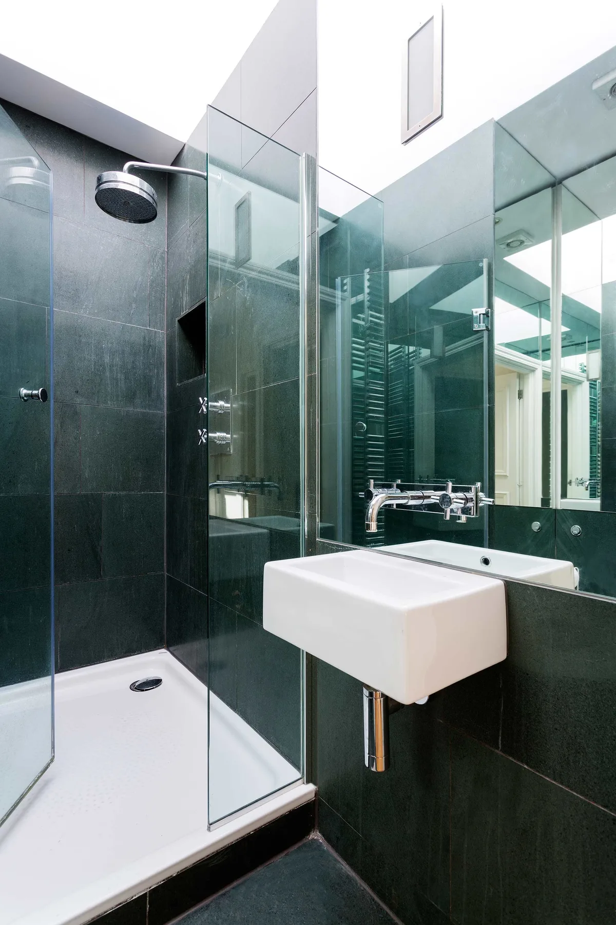 A modern bathroom with a glass shower and a wall-mounted sink.