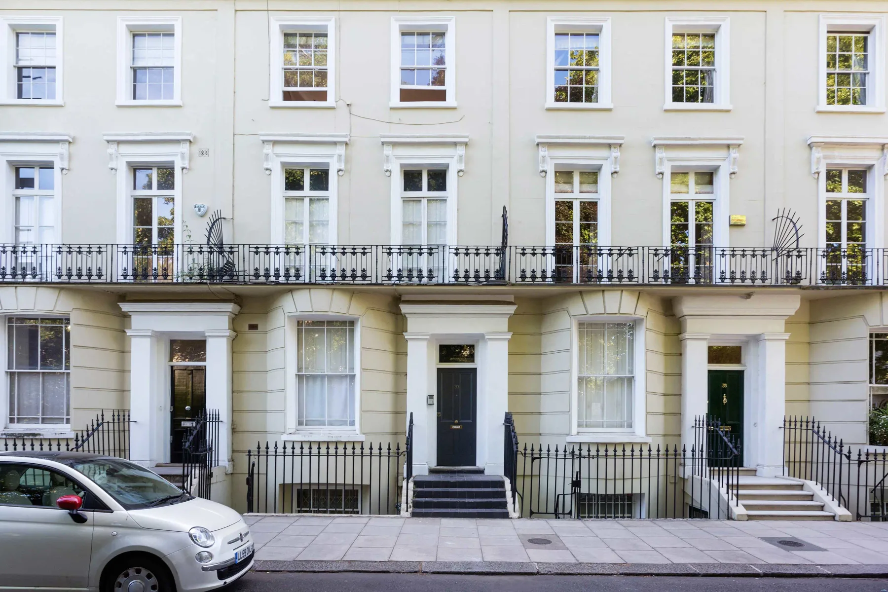A row of pale townhouses with sash windows and street-level entrances.