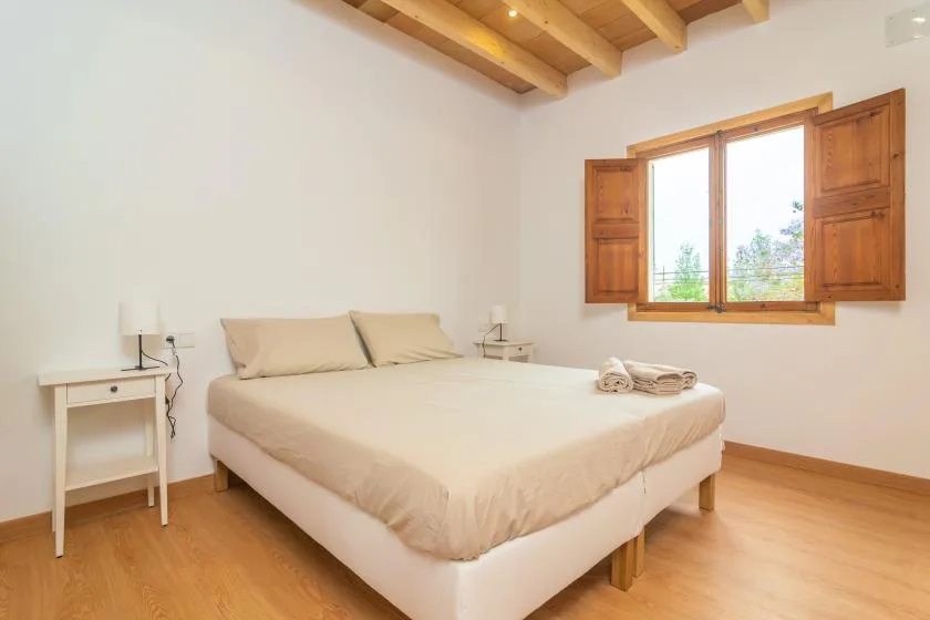 Un dormitorio con una cama bajo una ventana con contraventanas de madera.