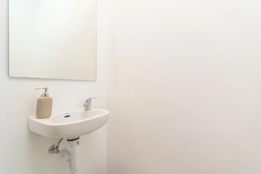 Un lavabo de baño con grifo y dispensador de jabón debajo de un espejo.