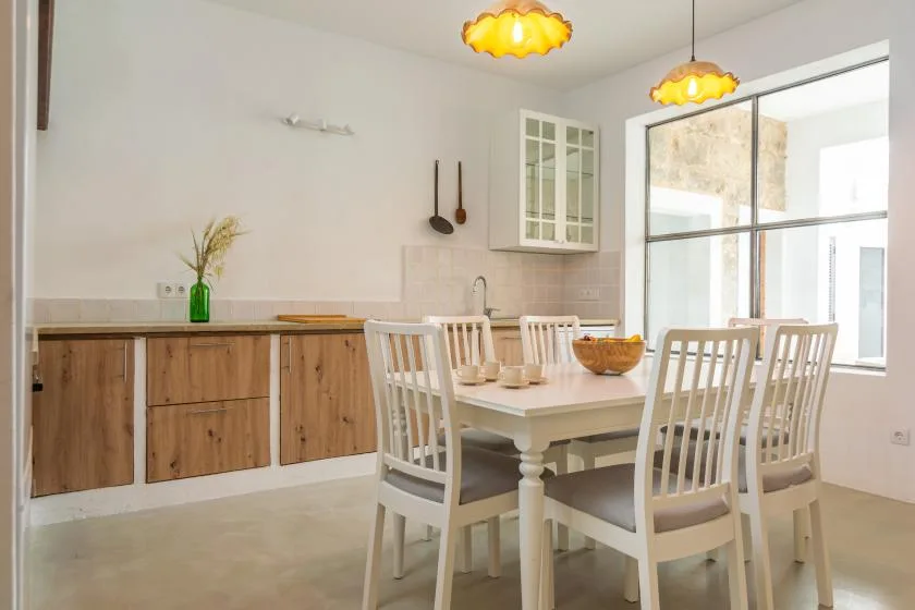 Un comedor con una mesa blanca y sillas junto a grandes ventanas.