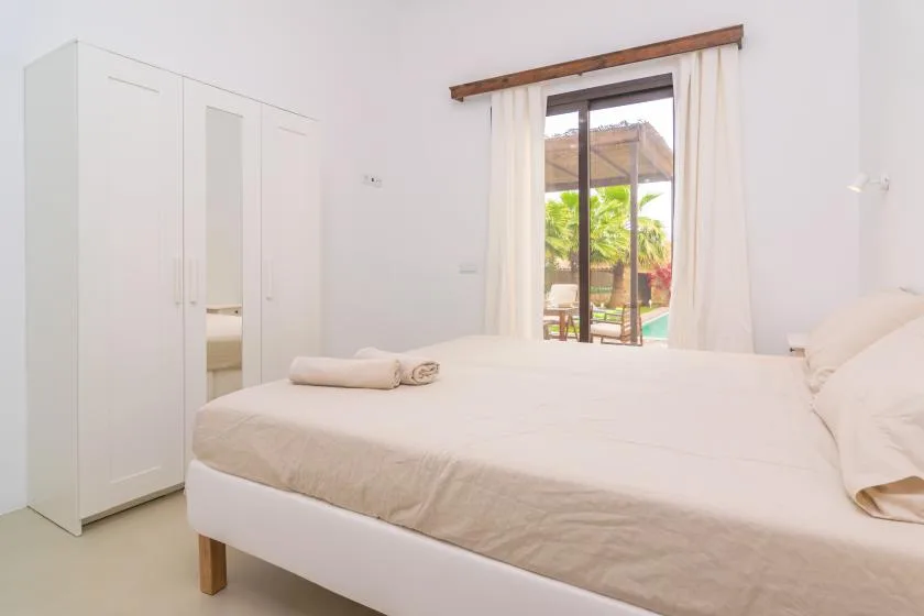 Un dormitorio luminoso con una cama y una ventana con vistas a la vegetación.
