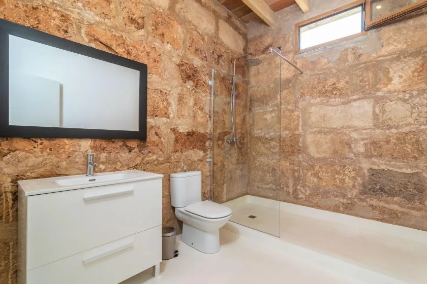 Un baño con un mueble de lavabo blanco, inodoro y mampara de ducha de vidrio.