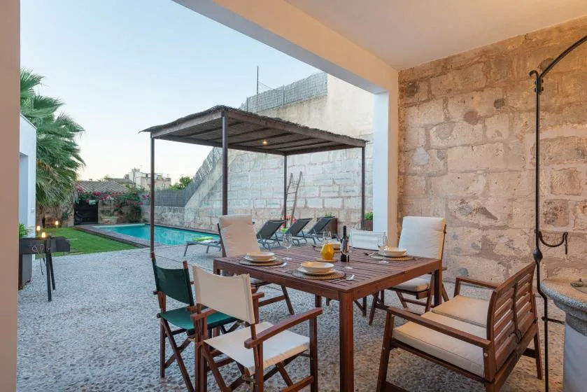 Una zona de comedor cubierta en el patio, junto a una piscina.