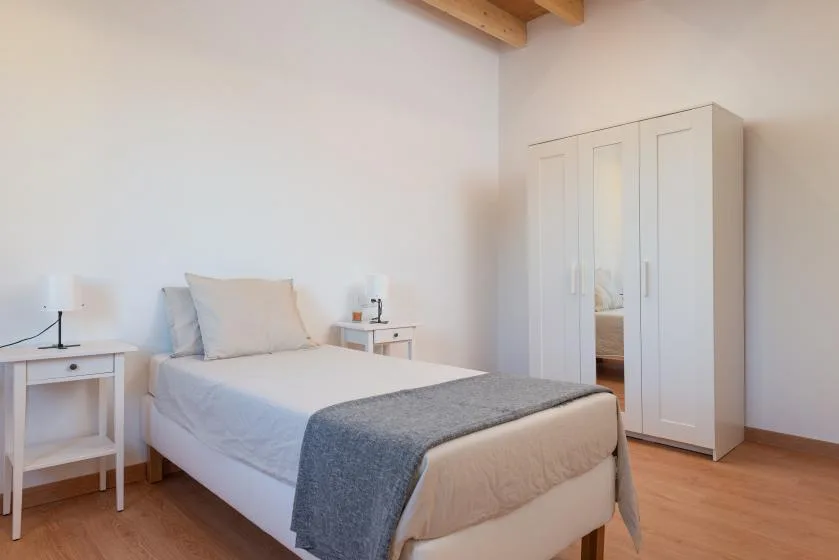 Un dormitorio con una cama, mesitas de noche y un armario.