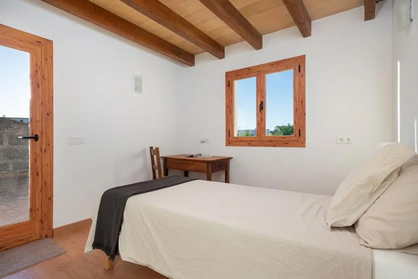 Un dormitorio con una cama, una mesa pequeña y vigas de madera a la vista.
