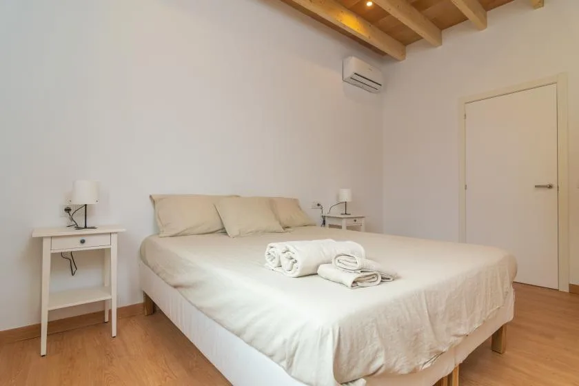 Un dormitorio con una cama bien arreglada y toallas dobladas.