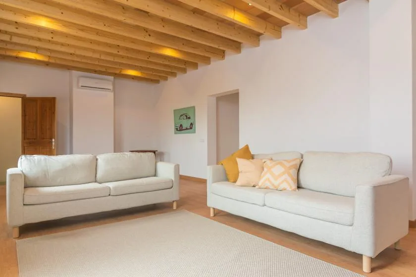 Una sala luminosa con dos sofás bajo un techo de madera expuesto.