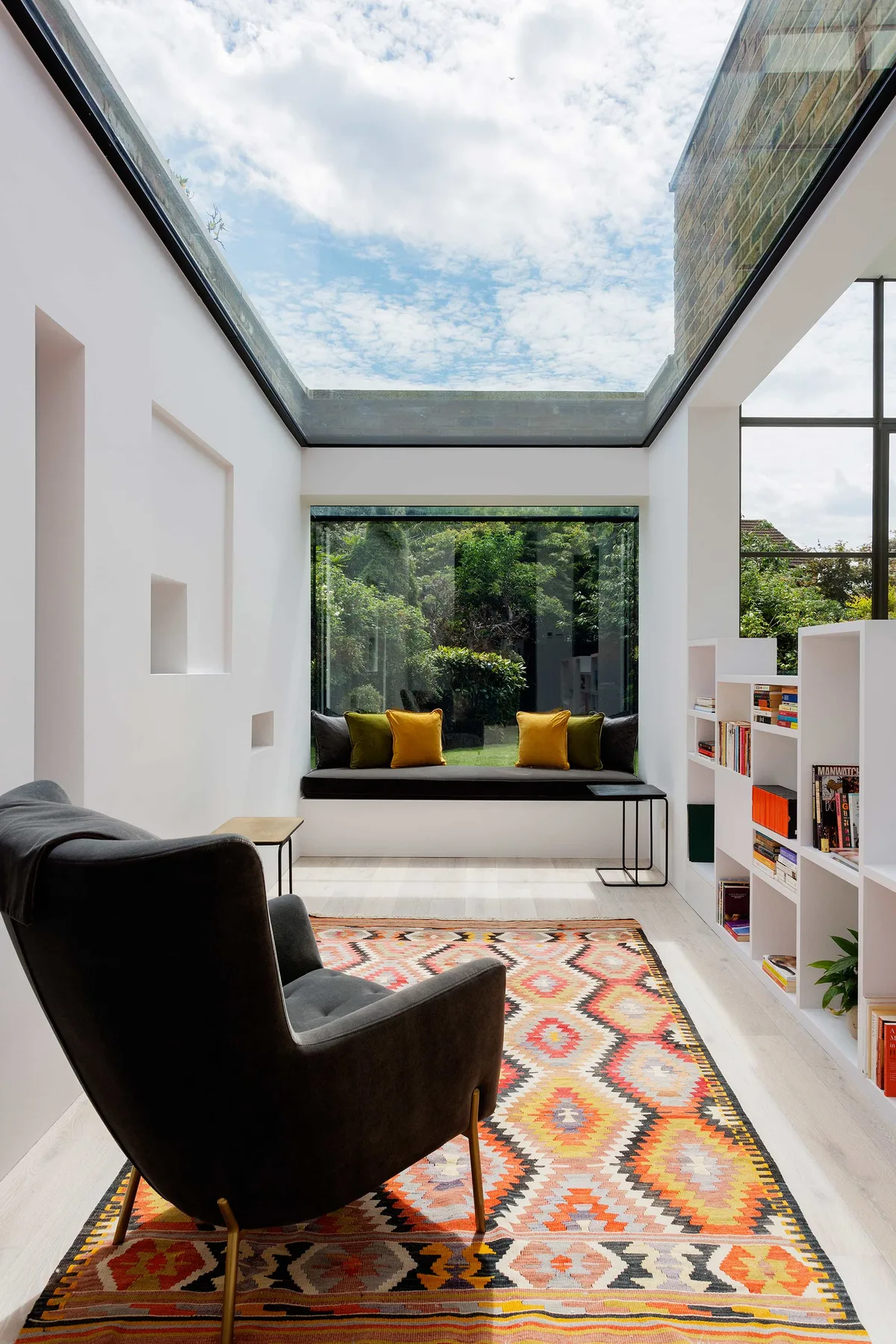 Una luminosa sala de estar moderna con tragaluz, un asiento junto a la ventana y una alfombra colorida.