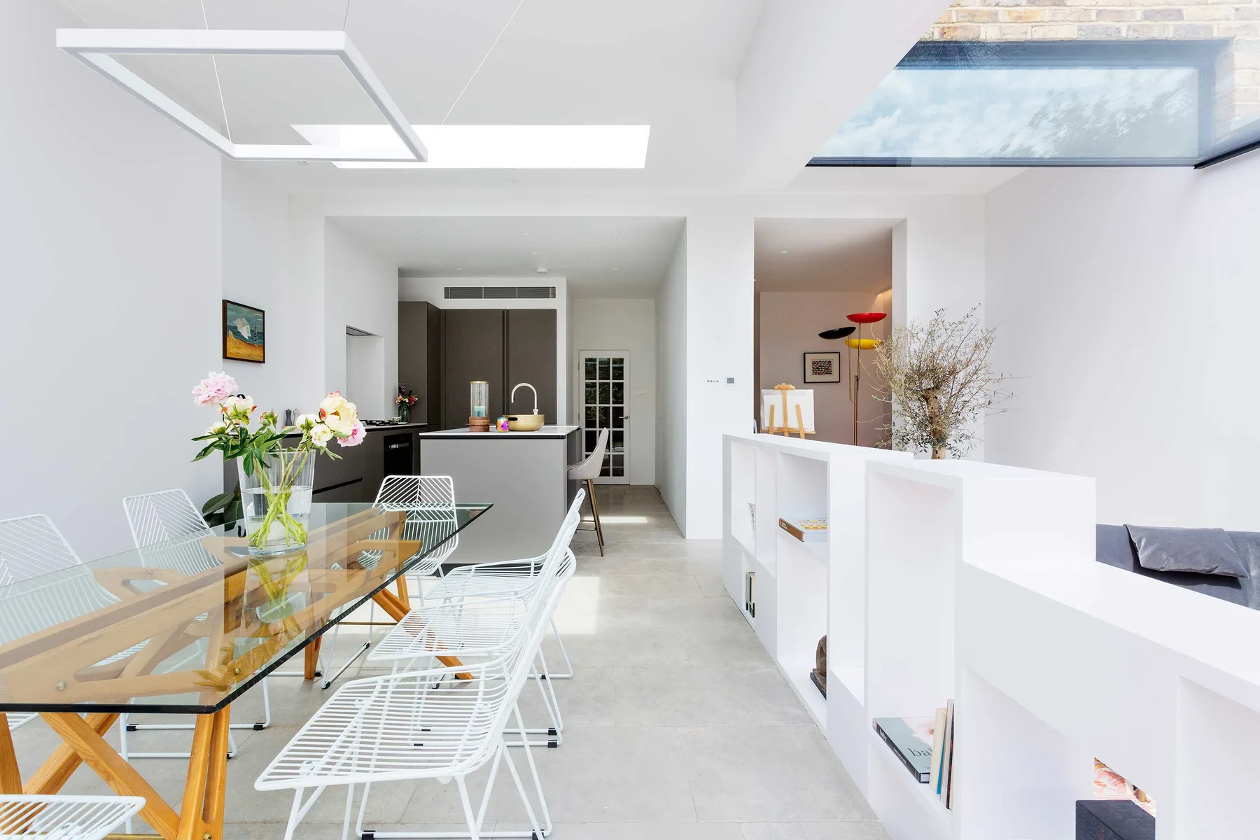 A bright open-plan dining and kitchen area with a glass dining table.