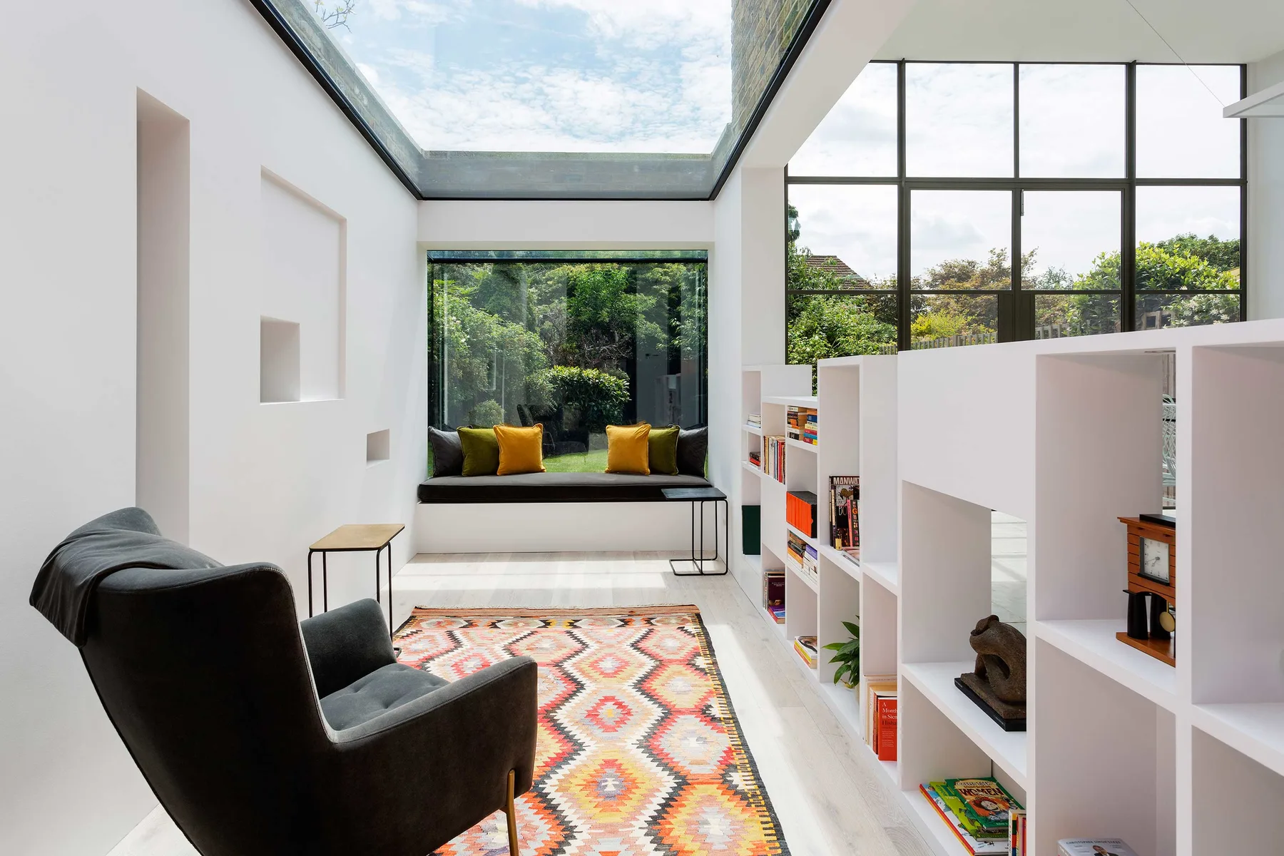 A bright living area with a skylight, colorful rug, and built-in shelving.