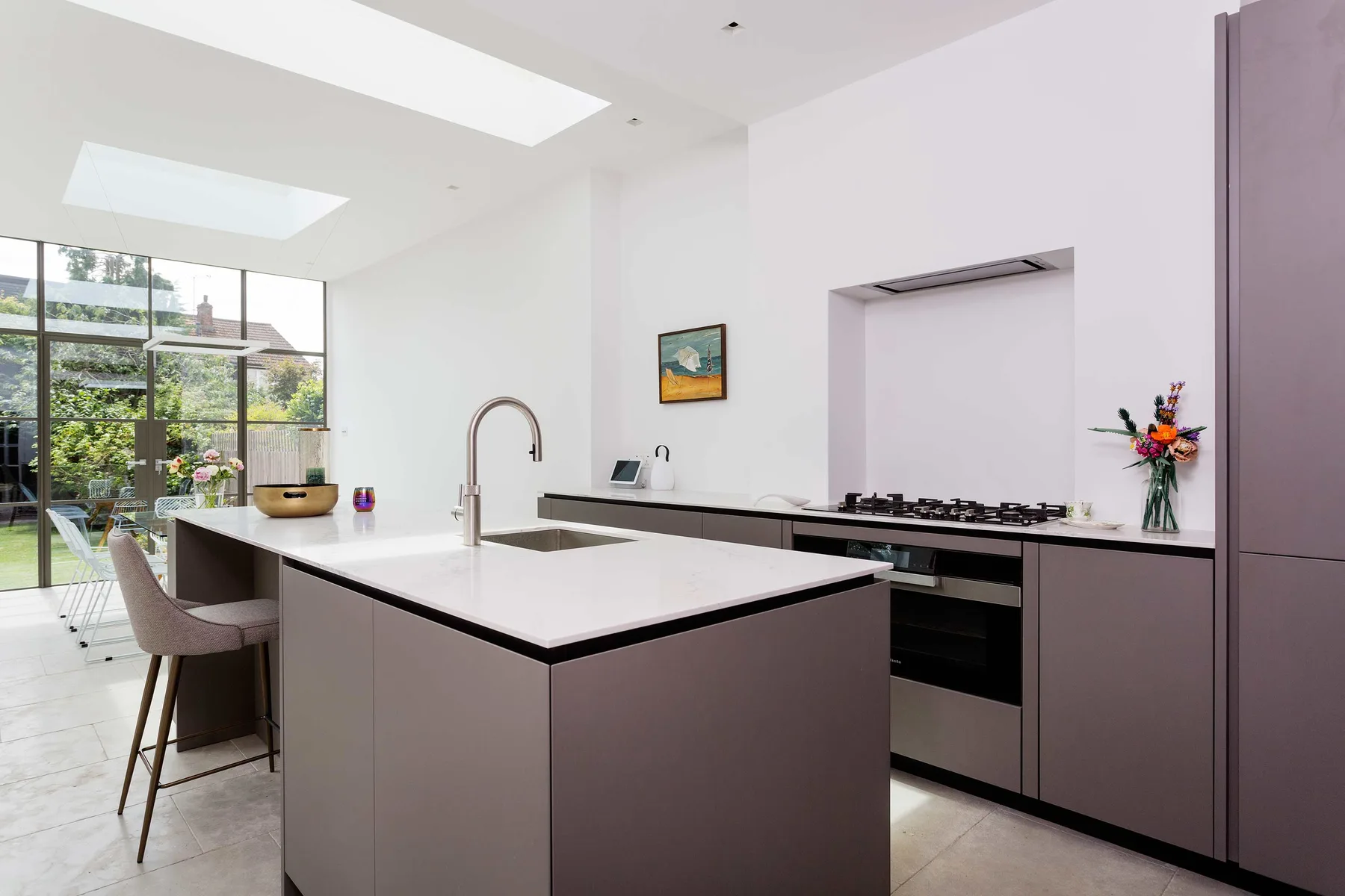 A bright modern kitchen with a large island and windows overlooking a garden.